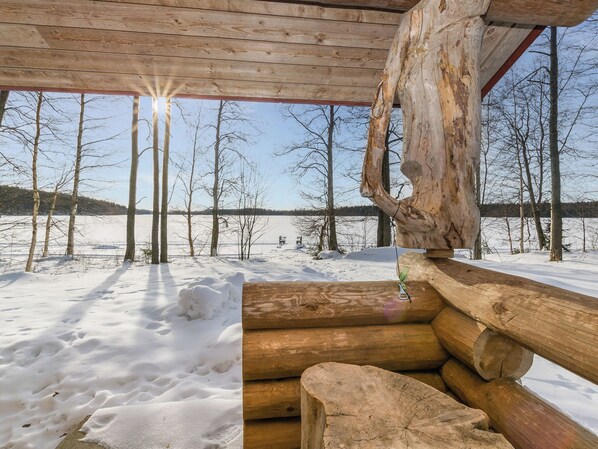 Una cabaña de madera con vistas a un paisaje nevado y un cuerpo de agua.