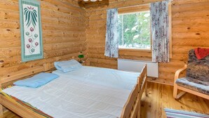 Een houten kamer met een bed, een stoel, een raam met gordijnen en een hanglamp.