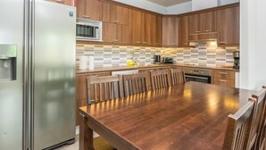 Una cocina moderna con armarios de madera, un refrigerador de acero inoxidable, un microondas y un salpicadero de azulejos.