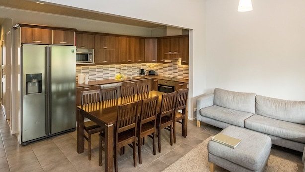 Una cocina moderna con microondas integrado, un refrigerador de acero inoxidable y un comedor con sillas de madera y una mesa.