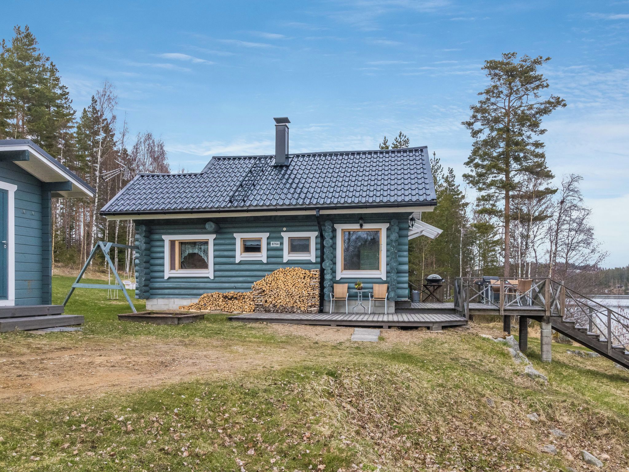 Eine Blockhütte mit Schornstein, einer Veranda und einem Holzstapel.