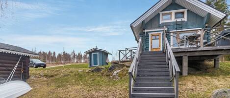 A log cabin with a wooden staircase leading to a deck.