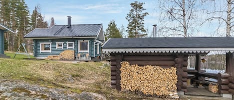 A log cabin with a deck and a small wooden structure with a roof.