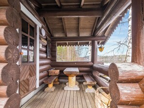 Une cabane en bois avec un porche couvert, des bancs et une table.