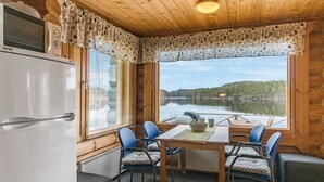 Una cabaña con una mesa de comedor, sillas y vista a un lago.