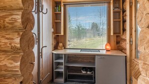 Una cocina compacta con estufa integrada, una ventana con persianas y un mueble pequeño.