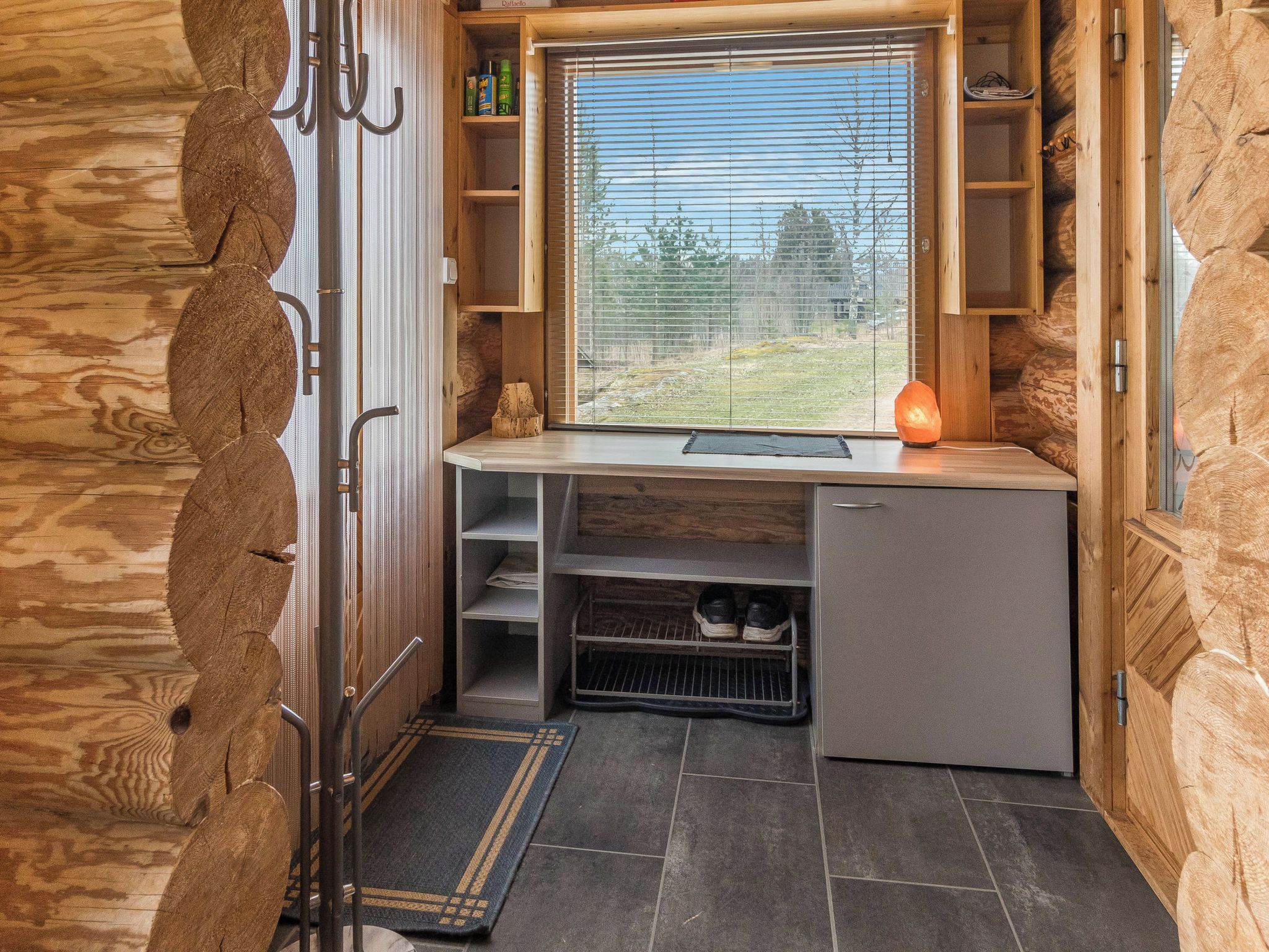 A compact kitchen with a built-in sink, wooden cabinets, and a window overlooking a grassy area.