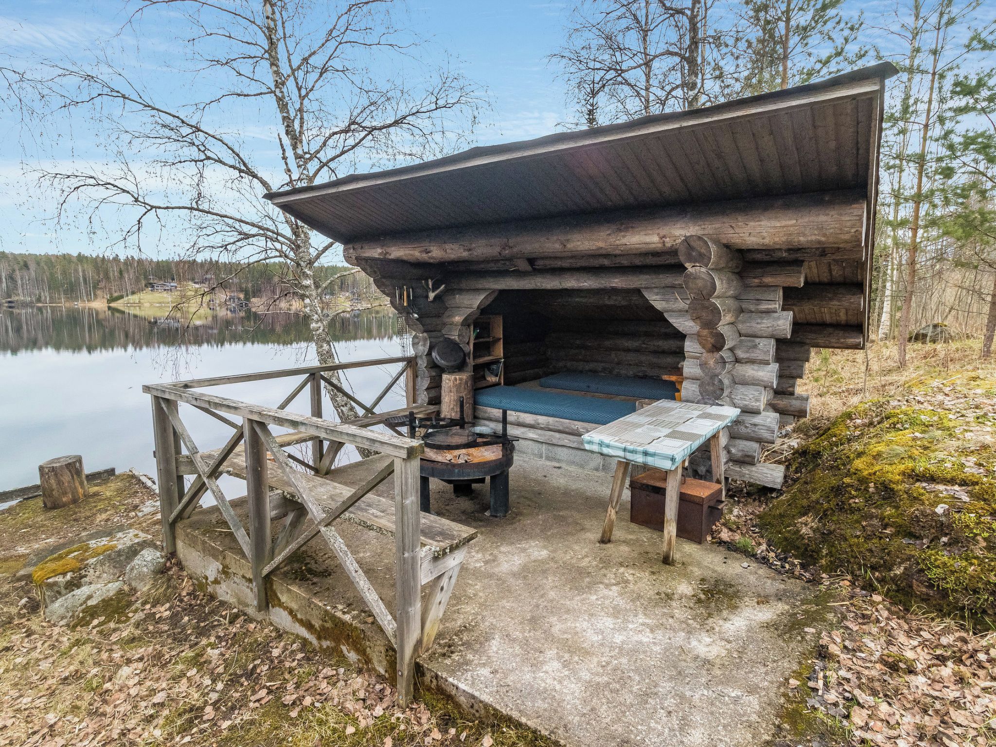 A rustic cabin with a stone fireplace, a small table, and a bench.