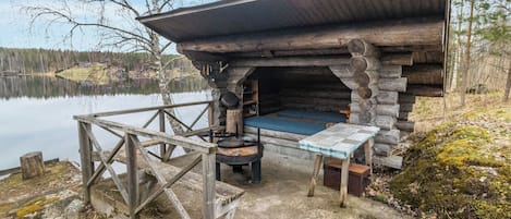 A rustic cabin with a stone fireplace, a small table, and a bench.