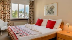 Une chambre d’hôtel avec un lit, une chaise, une table de chevet et une fenêtre avec des rideaux.