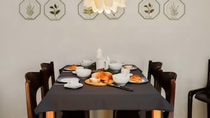 Une table à manger dressée avec des assiettes, des bols et une bougie, entourée de chaises.