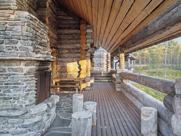 A log cabin with a stone exterior, wooden deck, and a bench.