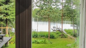 Näkymä ikkunasta järvenrantakiinteistöön, jossa on terassi ja laituri.