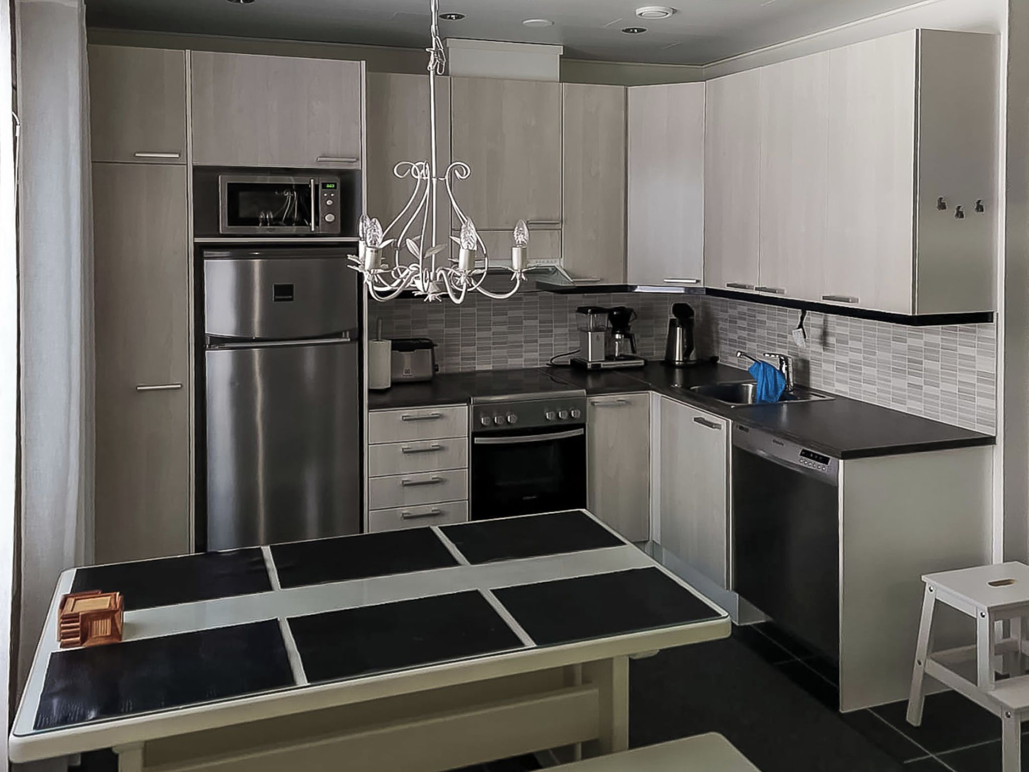 A modern kitchen with stainless steel appliances, a dining table, and a chandelier.