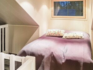 Une chambre à coucher avec un lit, des oreillers, une fenêtre et un berceau blanc.