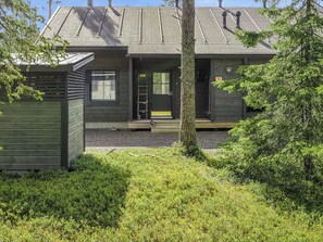 A modern two-story house with a dark exterior, a front porch, and a small front yard.