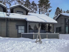 A two-story house with a covered patio area and a snow-covered roof.
