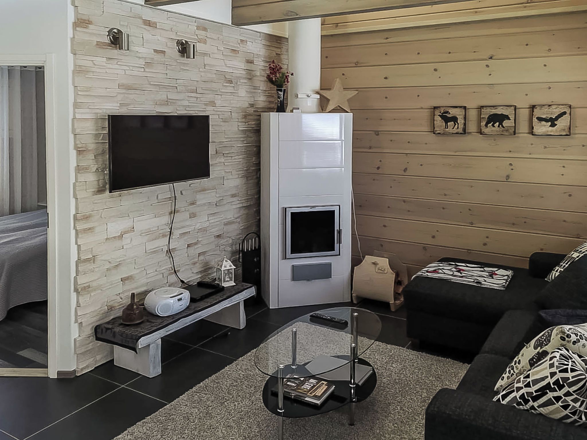 A modern living room with a stone wall, a fireplace, a flat-screen TV, a sofa, and a coffee table.