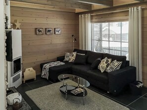 A cozy living room with a sectional sofa, a glass coffee table, and a fireplace.