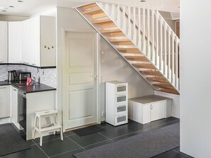Een moderne keuken met een inbouwfornuis, een kleine eethoek en een trap naar een hoger gelegen verdieping.