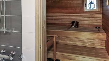 Ett ångrum med träbänkar, ett litet bord och ett fönster med utsikt över en byggnad.