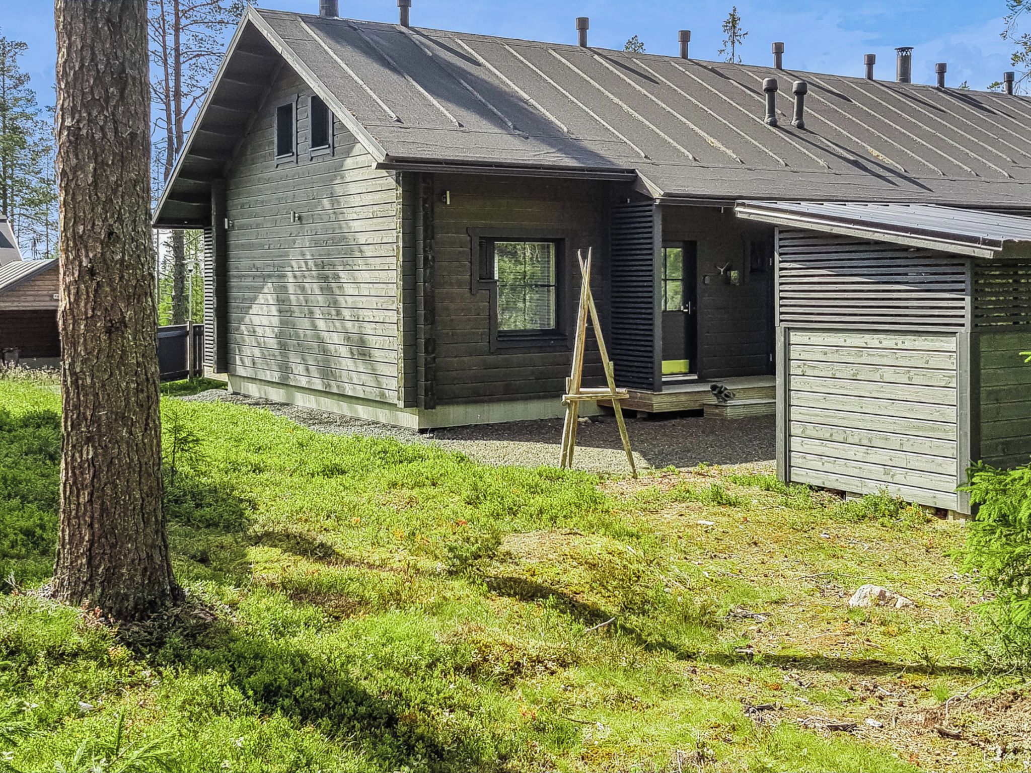 A wooden house with a sloped roof, a front porch, and a garage.
