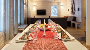 A dining table set for a meal with a red table runner, surrounded by chairs. - Tervakko by Interhome (Sodankylä)