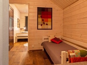 A cozy wooden room with a bed, a small table, and a wall-mounted artwork. - Tervakko by Interhome (Sodankylä)