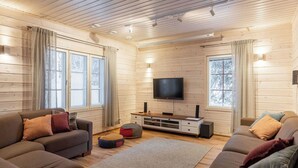A cozy living room with wooden walls, a flat-screen TV, two sofas, and a coffee table. - Tervakko by Interhome (Sodankylä)