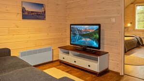 A cozy room with a wooden interior, a flat-screen TV on a wooden stand, a sofa, and a bed. - Tervakko by Interhome (Sodankylä)