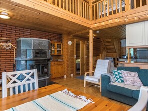 Interior acogedor de una cabaña con chimenea, muebles de madera y una zona de cocina.