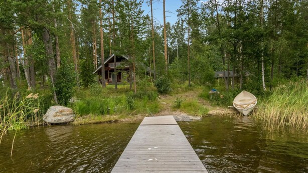 Un muelle de madera que lleva a una cabaña rodeada de un bosque.