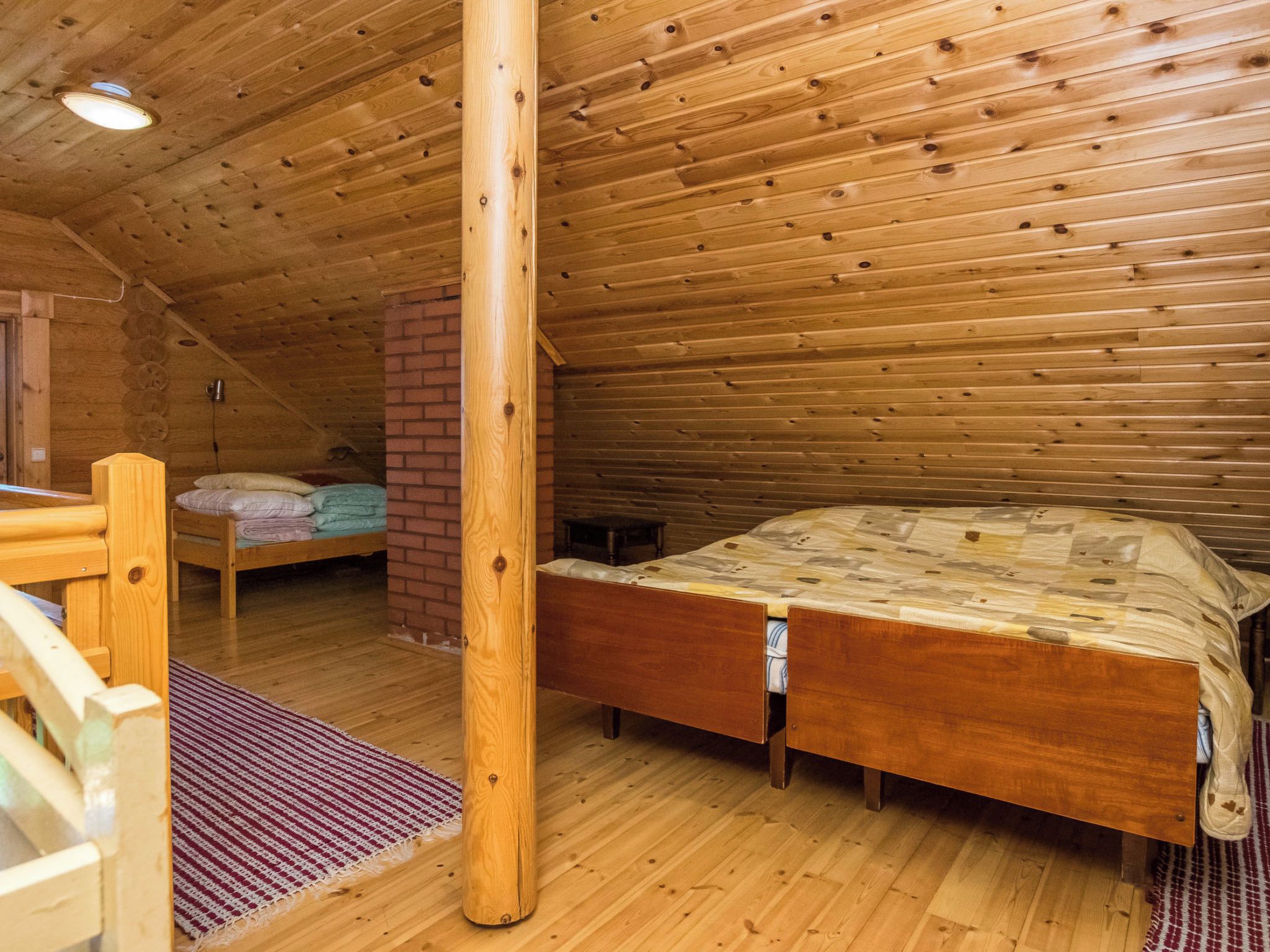 Un intérieur en bois avec un lit, un mur en briques et un plafond en bois.