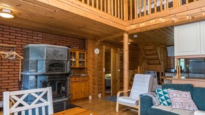 Un interior de cabaña acogedor con chimenea, muebles de madera y un balcón.