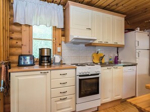 Una cocina pequeña con armarios de madera, una estufa, una cafetera y un refrigerador.