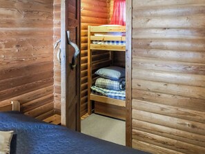 A wooden cabin interior with a bunk bed, a door, and a small window.