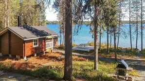 Een chalet met terras met uitzicht op een meer, omringd door bomen.