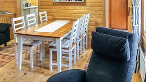Een houten interieur met een eettafel en stoelen, een bank en een houten deur.
