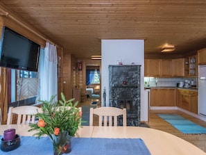 Tunnelmallinen mökin sisustus, jossa on ruokailutila, olohuone ja keittiö.