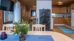 A cozy cabin interior with a dining area, a fireplace, wooden cabinets, and a television. - Aamuntorkku by Interhome (Punkaharju)