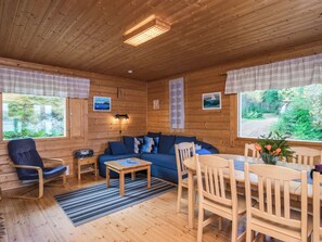 L’intérieur d’un chalet accueillant, avec un plafond en bois, un canapé, une table à manger et des chaises.
