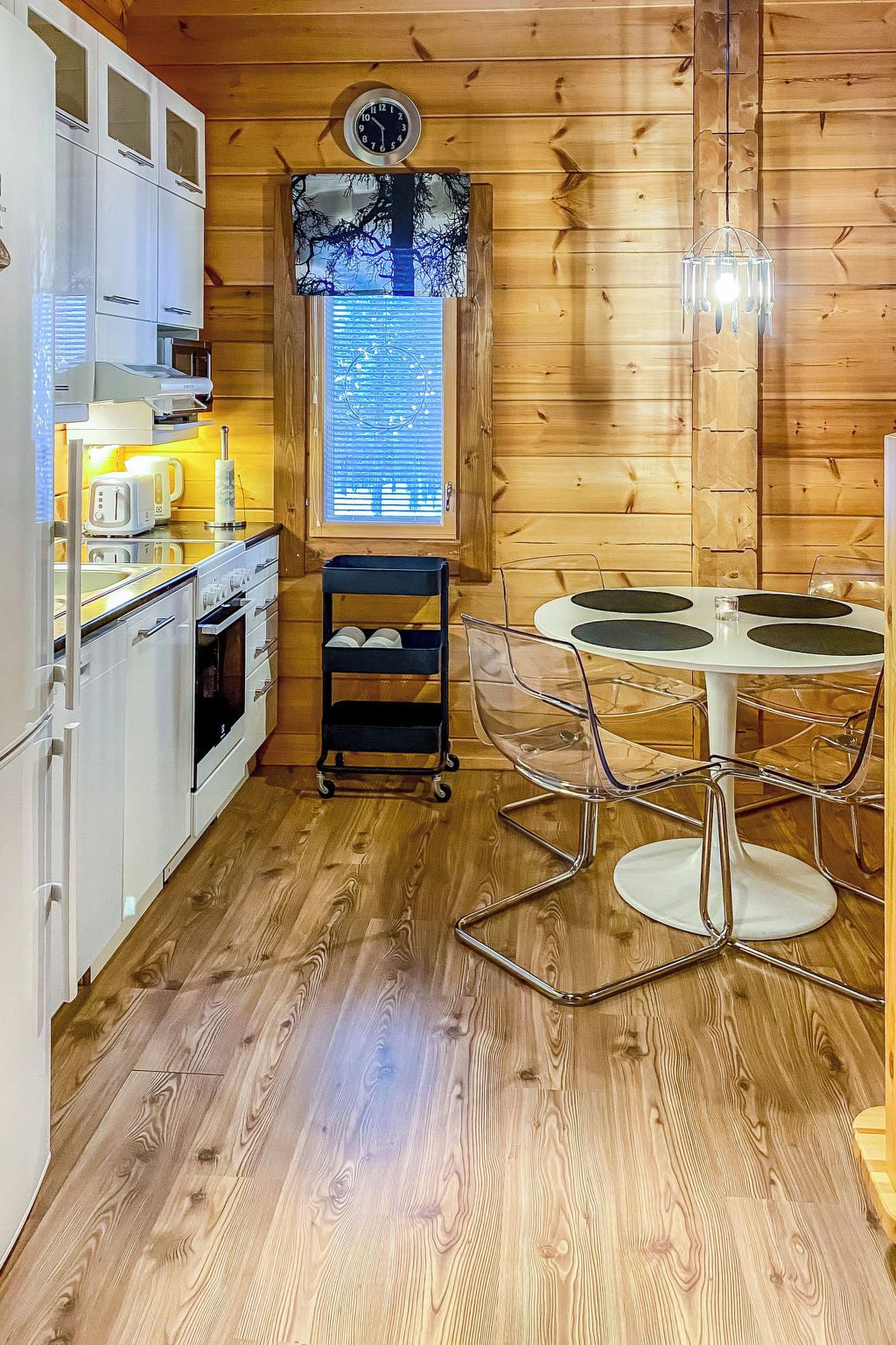 A compact kitchen with modern appliances, a dining area with a glass table, and a wooden interior.