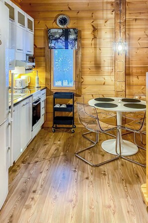 A compact kitchen with modern appliances, a dining area with a glass table, and a wooden interior.