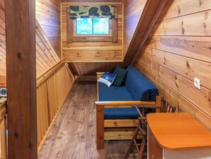 A cozy cabin interior with a wooden floor, a sofa with cushions, a small table, and a window with a view. - Utsunusko a by Interhome (Kittilä)