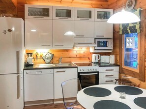 A compact kitchen with a refrigerator, microwave, stove, and sink. - Utsunusko a by Interhome (Kittilä)