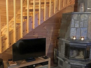 A wooden staircase, a stone fireplace with two lit candles, and a television on a stand. - Utsunusko a by Interhome (Kittilä)