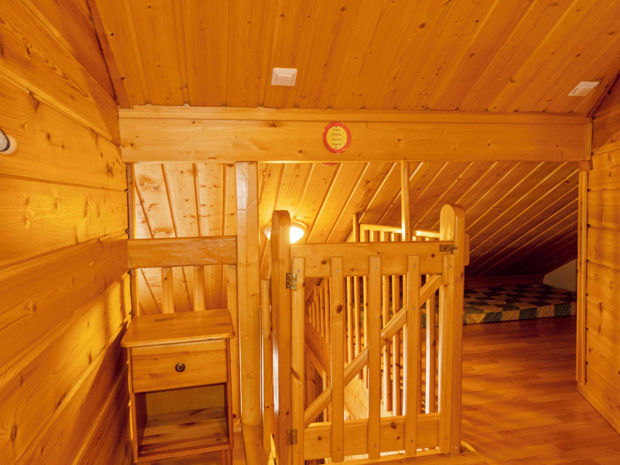 Puisella lattialla on puinen ovi, pieni puinen pöytä ja ruutukuvioinen matto.