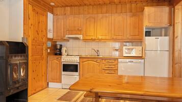 A kitchen with wooden cabinets, a stove, a microwave, and a refrigerator.