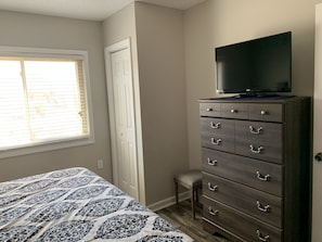 A bedroom with a bed, a dresser, a television on top of the dresser, and a window with blinds. - Gatlinburg Chateau 103 is a beautiful 2BR condo and a short walk to downtown (Gatlinburg)