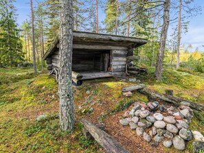 A rustic log cabin surrounded by a forest with a pile of rocks in front. - Kurjenrahka by Interhome (Turku)